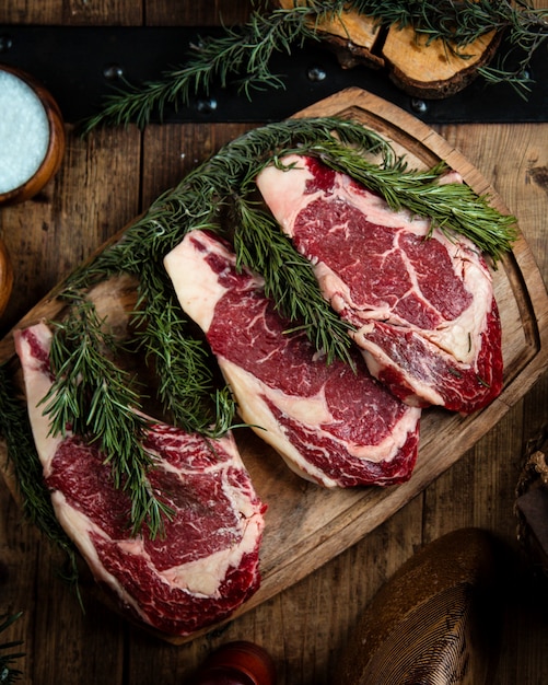 Free photo fresh rib eye steaks on wooden board