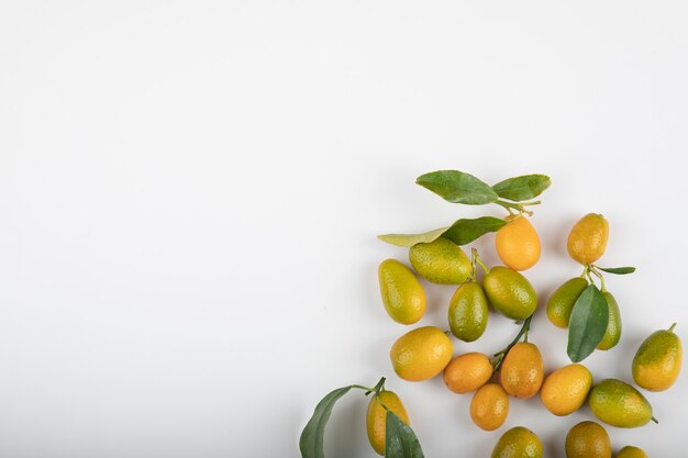 Fresh ripe kumquats with leaves on white.