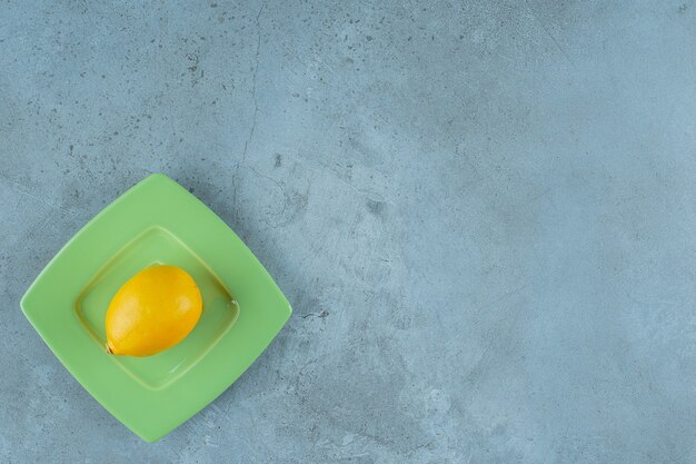 Fresh ripe lemon on a coaster, on the marble background.