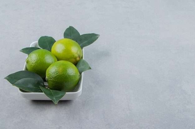 Fresh ripe limes on white plate