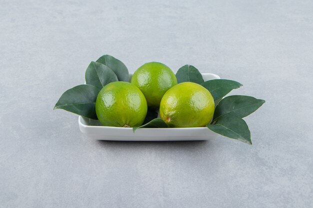 Fresh ripe limes on white plate