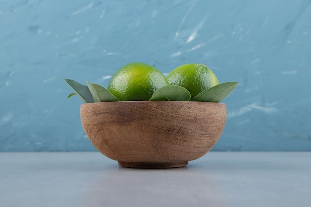 Free photo fresh ripe limes in wooden bowl.