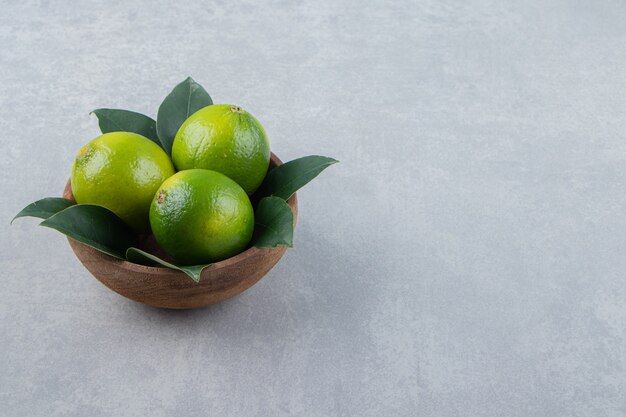 Fresh ripe limes in wooden bowl