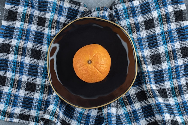 Fresh ripe orange on black plate.