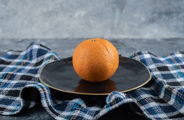 Fresh ripe orange on black plate. 