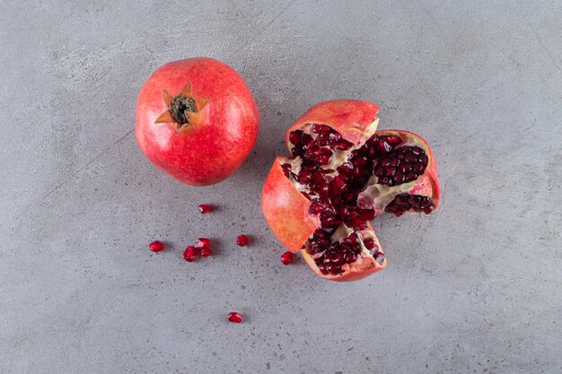 Fresh ripe pomegranates with seeds placed on stone background. 