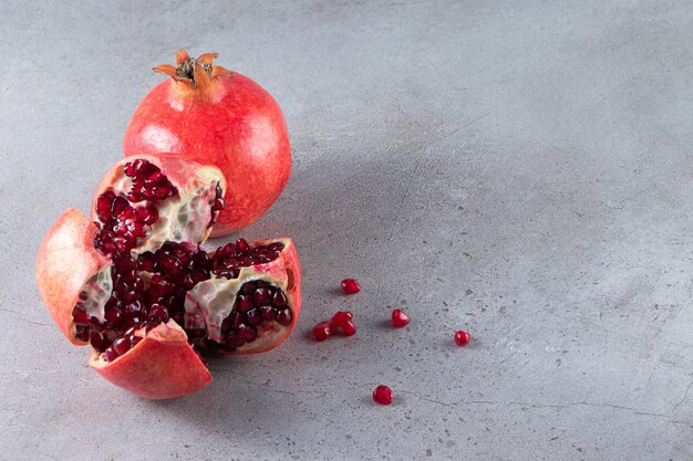 Fresh ripe pomegranates with seeds placed on stone background. 