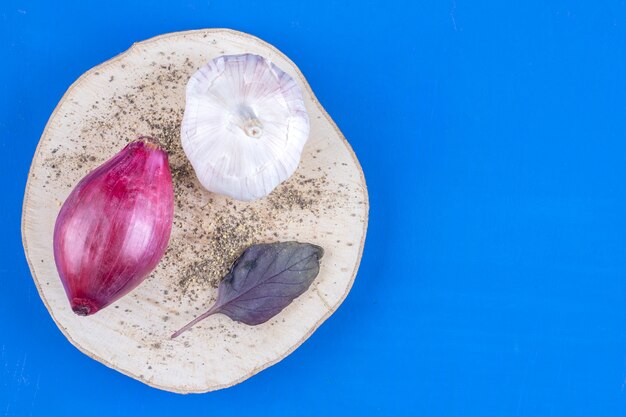Fresh ripe purple onion and garlic on wood piece. 