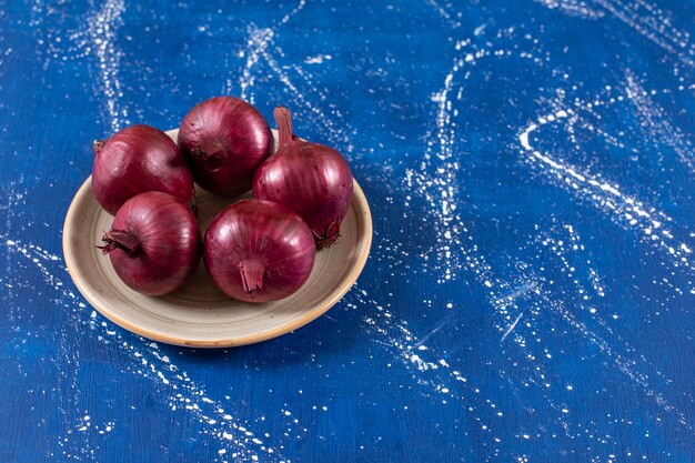 fresh ripe red onions placed on ceramic plate.