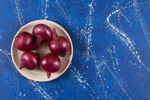 Foto gratuita cipolle rosse mature fresche disposte sul piatto di ceramica