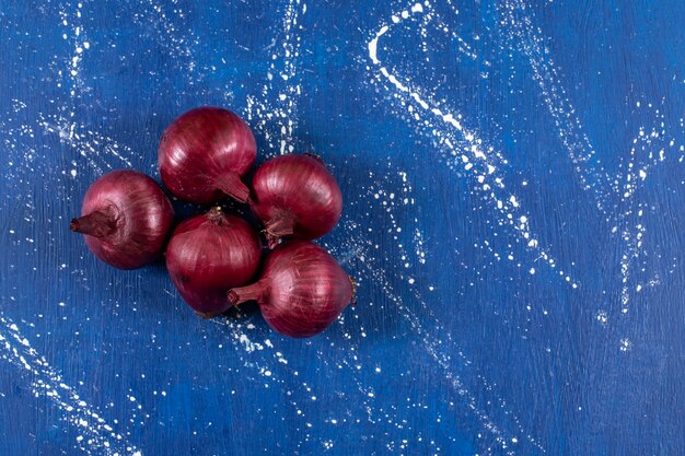 Fresh ripe red onions placed on marble surface. 