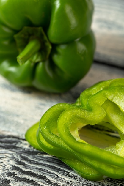 Free photo fresh ripe and sliced green bell paper on grey wooden desk