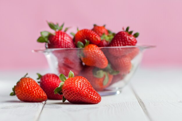 Fresh ripe strawberry in glass bowl on wood