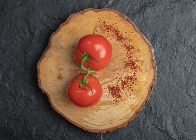 Fresh ripe tomatoes with red hot chili pepper on wooden board.