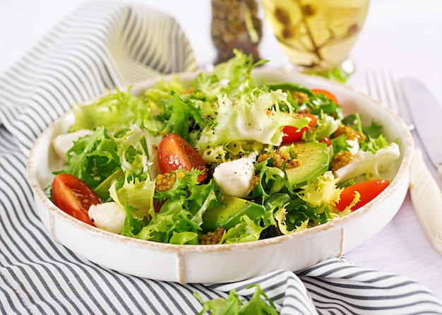 Fresh salad with avocado, tomato, olives and mozzarella in a bowl.  Fitness food. Vegetarian meal.