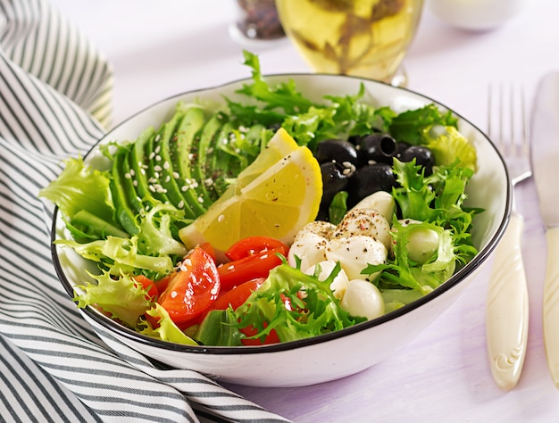 Fresh salad with avocado, tomato, olives and mozzarella in a bowl