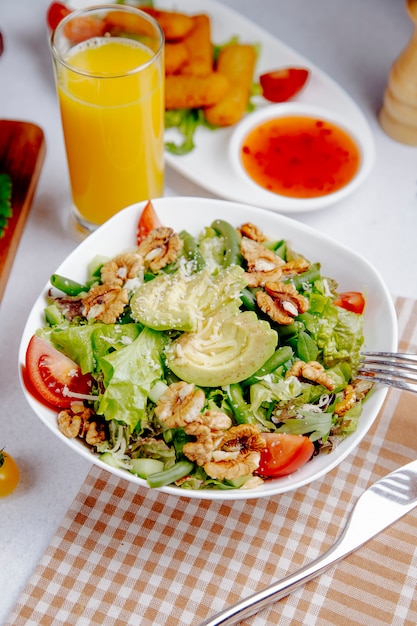 Fresh salad with avocado and walnuts on table