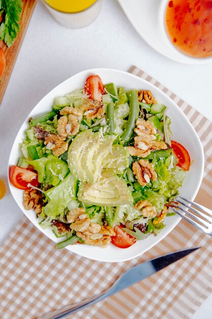 fresh salad with avocado, walnuts and tomatoes on table