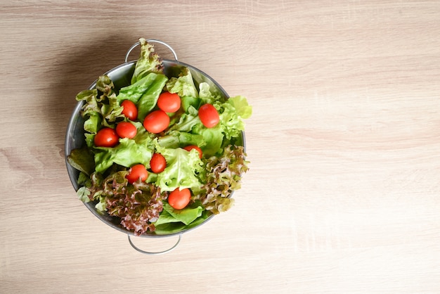 Fresh salad with vegetables and greens on wooden table. Healthy food concept.