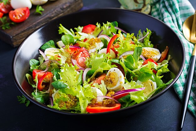 Свежий салат с овощами, помидорами, красным луком, листьями салата и перепелиными яйцами. Концепция здорового питания и диеты. Вегетарианская пища.