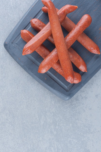 Free photo fresh salami on black wooden cutting board.