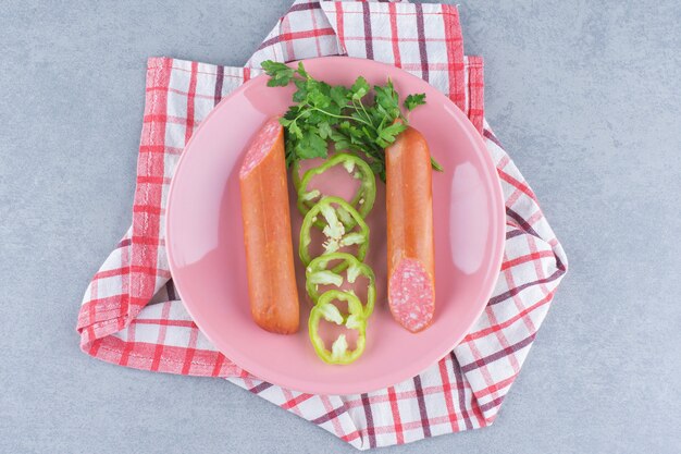 Fresh salami on pink plate with peppers. 