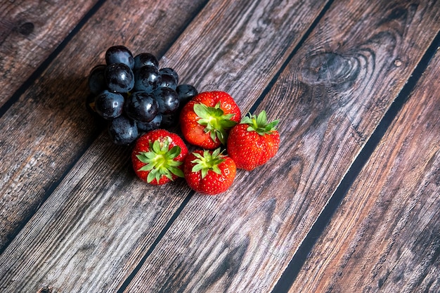 Fresh Scottish strawberries and black grapes on top of wooden table.