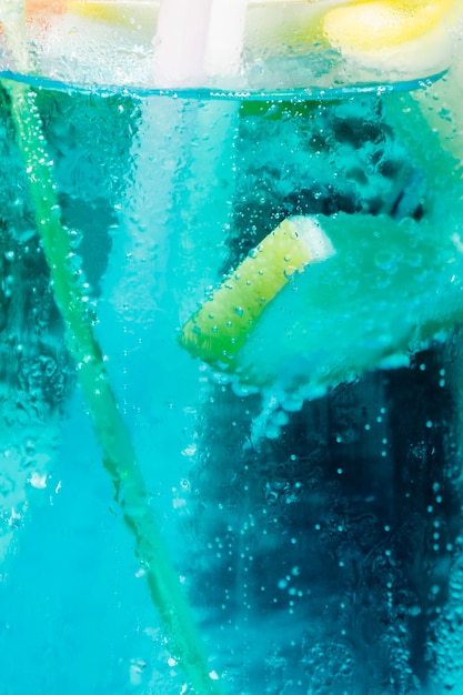 Fresh slice of lemon floating in blue cold cocktail with bubbles