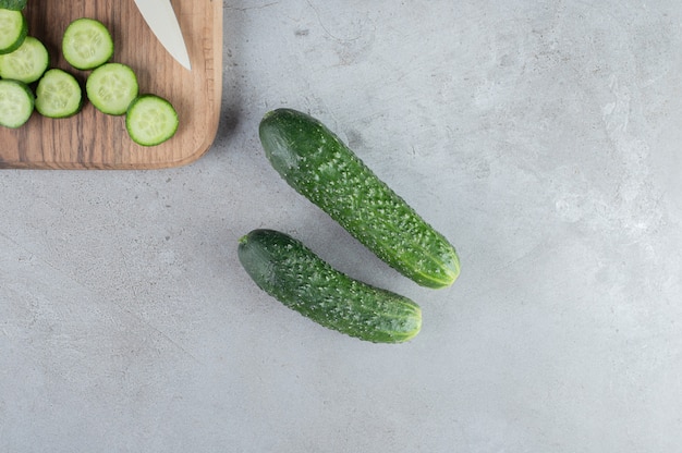 Fresh sliced cucumbers with knife on a wooden board . High quality photo