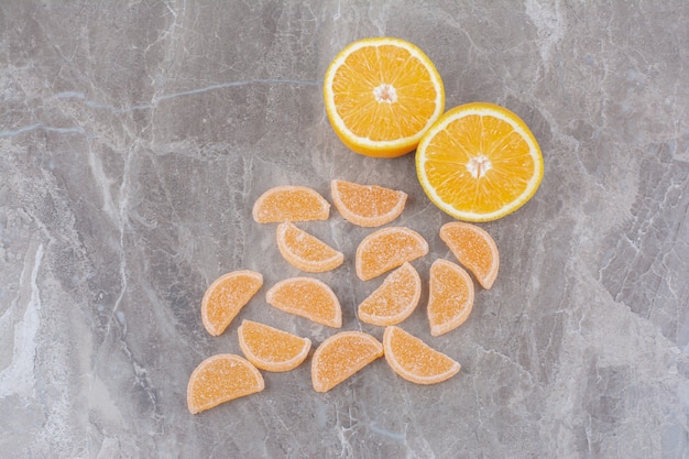 Бесплатное фото Свежие дольки апельсина со сладким мармеладом на мраморном фоне.