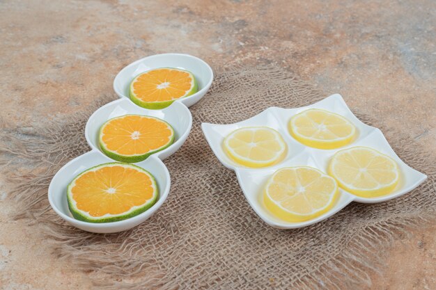 Fresh slices of orange and lemon on various plates. 