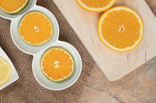 Свежие дольки апельсина на различных тарелках.