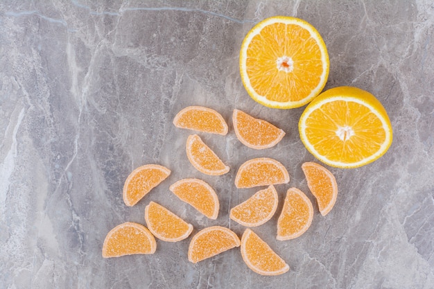 Free photo fresh slices of orange with sweet marmalades on marble background.