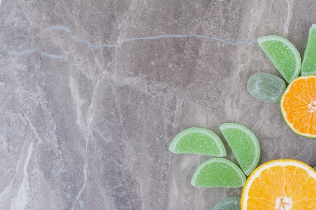 Fresh slices of orange with sweet marmalades on marble background.