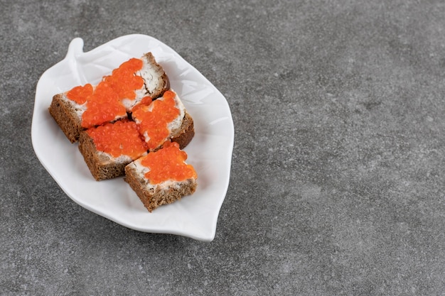 Free photo fresh small sandwiches on white plate over grey surface.