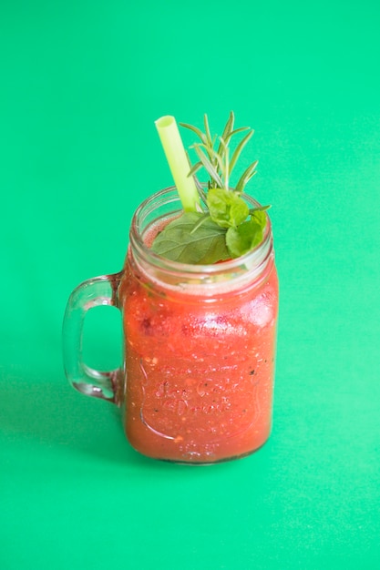 Fresh smoothie in mason jar on green background