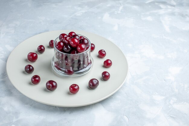 fresh sour cherries inside plate on light white