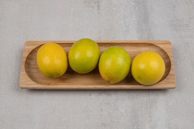 Fresh sour lemons on wooden plate.