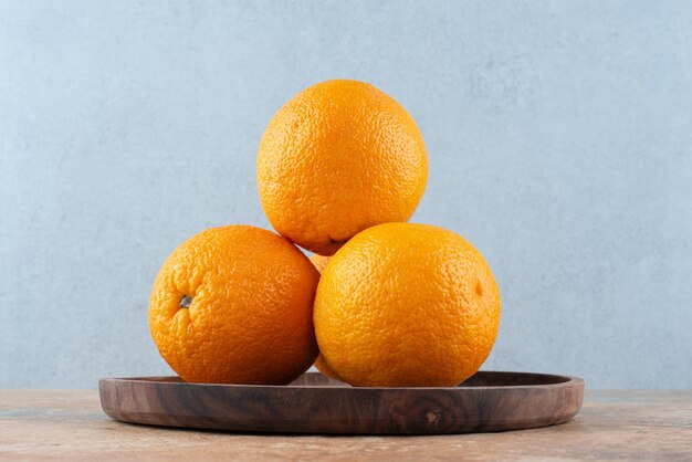 Свежие кислые апельсины на деревянной тарелке
