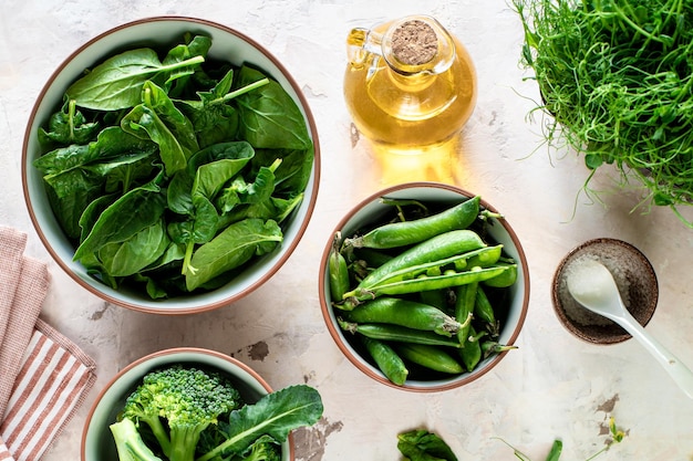 Fresh spinach leaves green peas broccoli in a bowl top view