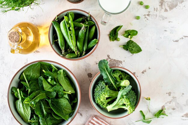 Fresh spinach leaves green peas broccoli in a bowl top view