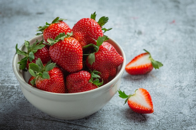 Fresh strawberries in a bowl on old dark background