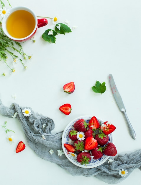 Fresh strawberry fruits, flowers, leaves on white wood table