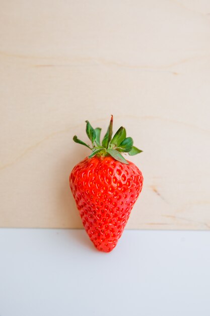 Fresh strawberry side view on light wood wall and white