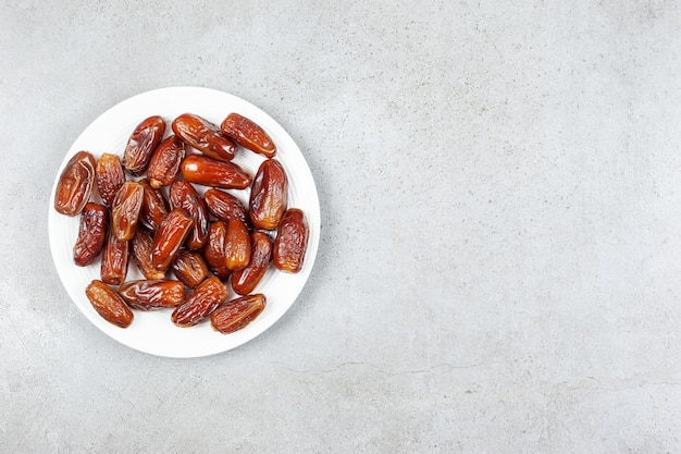 A fresh and succulent plate of dates on marble background. High quality photo