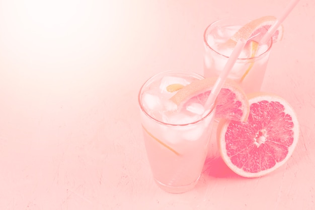 Fresh summer healthy diet beverage and grapefruit on pink background