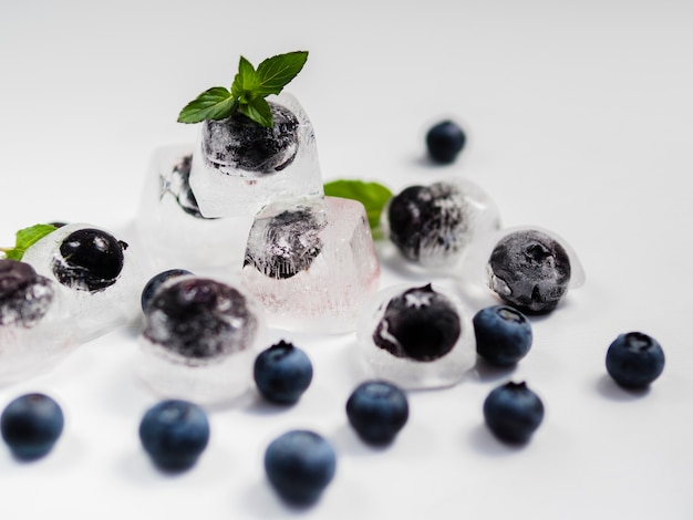 Fresh sweet blueberry and black currant in ice on white background