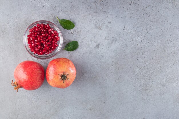 Fresh sweet pomegranates with leaves placed on stone background. 