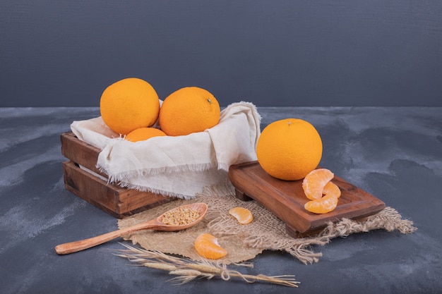 Mandarini freschi in scatola di legno e fette di mandarini su tela da imballaggio.