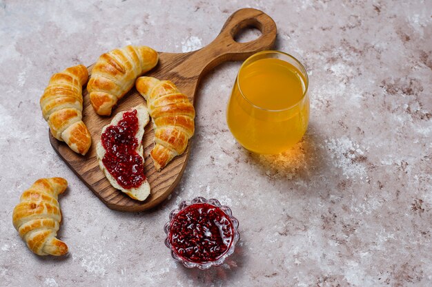 Fresh tasty homemade croissants with raspberry jam on grey-white . French pastry